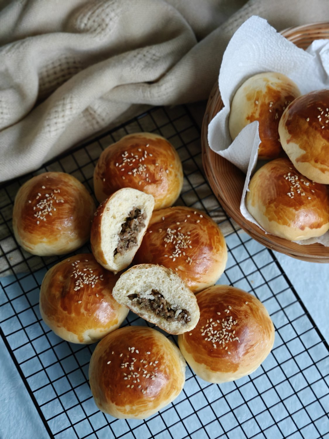 Golden sesame buns with minced beef filling, one split open to show the filling